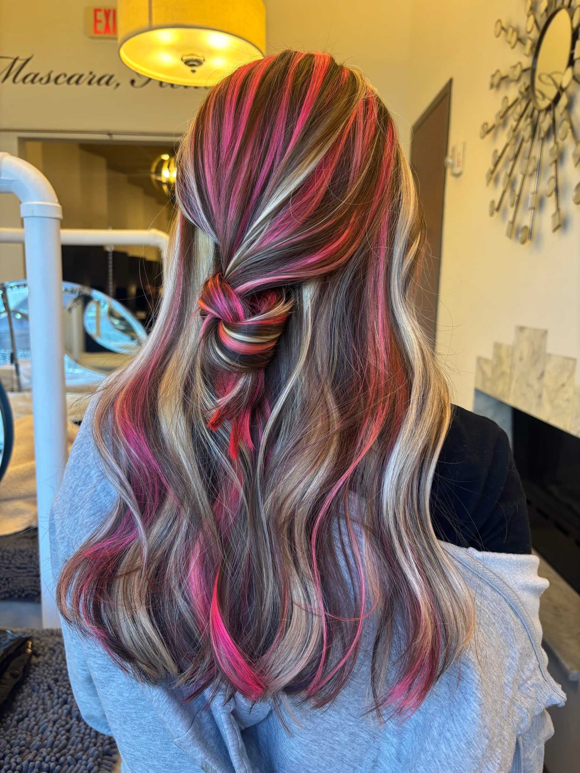 Hair with vibrant pink and blonde highlights styled in a twisted half-updo.