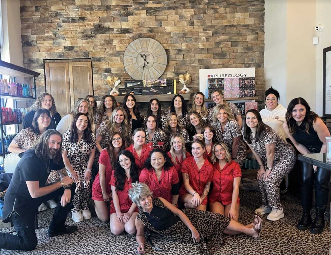Group of people in a salon, posing together in leopard print and red outfits.